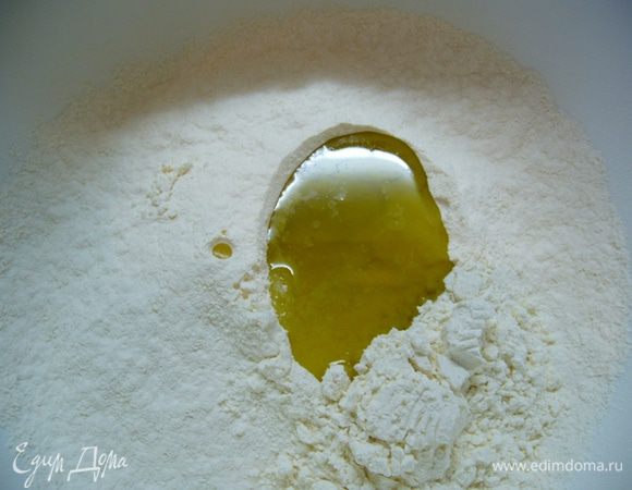 В миску просеять муку. Сделать в ней углубление, всыпать в него соль, влить оливковое масло.

