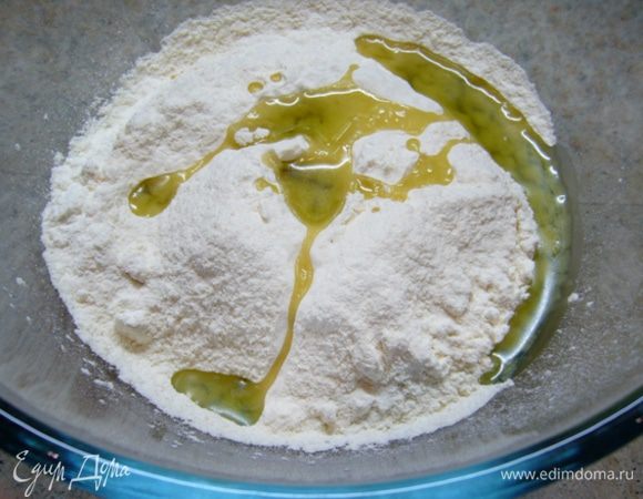 Муку просеять в чашу.
Подогреть воду до теплого состояния.
Добавить к муке соль, две столовые ложки оливкового масла и теплу воду, замесить тесто.
