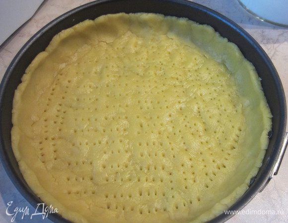 Выкладываем тесто в форму 24 см и распределяем руками, делаем бортики. Дно протыкаем вилкой. Оставляем немного теста для посыпки.