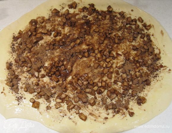 Увеличившееся в 2 раза тесто обмять и раскатать в большой пласт размером примерно 40x60cм. Смазать раскатанное тесто растопленным сливочным маслом. Распределить яблочно-коричную начинку по всей поверхности теста, не заходя на края.