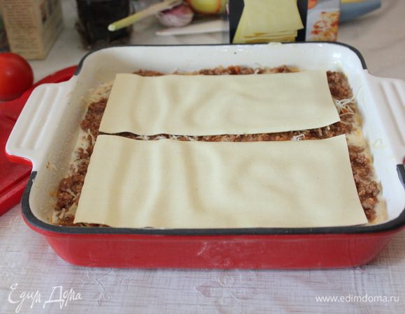 На дно жаропрочной формы влейте немного сливочного соуса и затем выложите листы лазаньи. Листы лазаньи предварительно отваривать не нужно. В духовке за 30 минут они будут готовы. Самое главное - чтобы соуса было достаточно. Сверху равномерно распределите слой мясного соуса, присыпьте тертым сыром и снова накройте листами лазаньи.