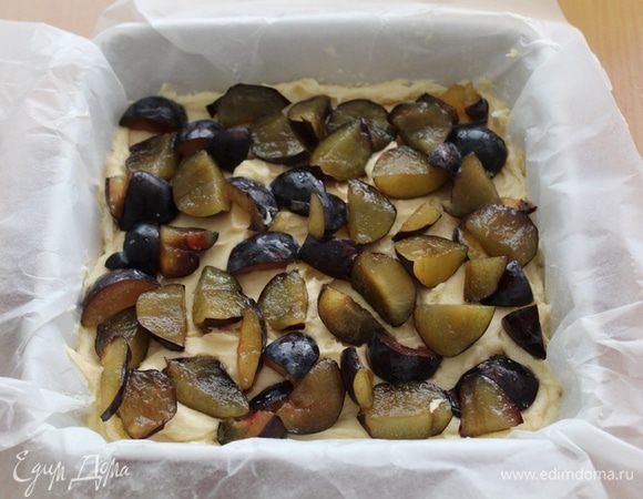 Выложить форму бумагой для выпечки, на нее выложить тесто (тесто получается довольно густое), поверх - порезанные сливы.