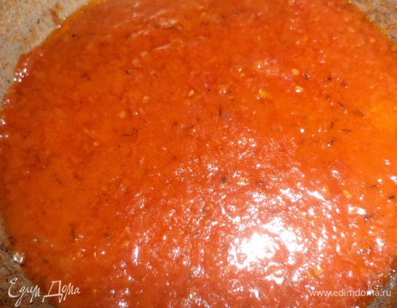 Разогреть оливковое масло в широкой сковороде, выложить в масло 2 зубчика чеснока, через 2 минуты вынуть чеснок.
Помидоры протереть на тёрке. Огонь под сковородой убавить до МИНИМУМА, сделать это нужно обязательно, иначе полплиты будет в помидорном соусе, добавить в сковороду протёртую помидорную массу, накрыть крышкой, тушить 10-15 минут, до загустения соуса. 
Посолить, приправить орегано и красным перцем. Перемешать, выключить огонь.