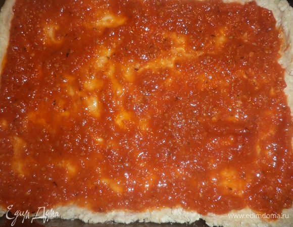 Противень смазать оливковым маслом. Тесто тонко раскатать, выложить тесто на противень, покрыть тесто соусом.
