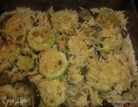 Выложить сверху на соус нарезанные тонкими кольцами помидоры и обжаренные баклажаны и кабачки, посыпать тёртым сыром и орегано. Выпекать при температуре 190 градусов 30 минут.