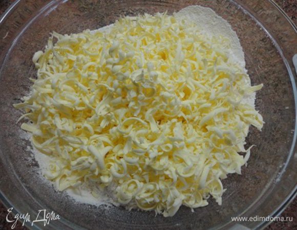 В миску просеять муку с разрыхлителем и солью, добавить 100 г сахара. Холодное масло натереть на крупной терке. Все слегка перетереть руками.