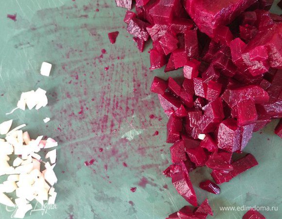 Вареную свеклу очистить, порезать на мелкие кубики, дольку чеснока измельчить.