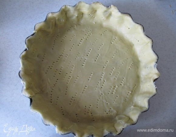 Охлажденное тесто раскатать между двумя листами пергамента. Выложить тесто в форму для тарта, распределить по всей форме, излишки теста удалить. Наколоть тесто по всей поверхности вилкой и отправить в холодильник еще на 30 мин.
