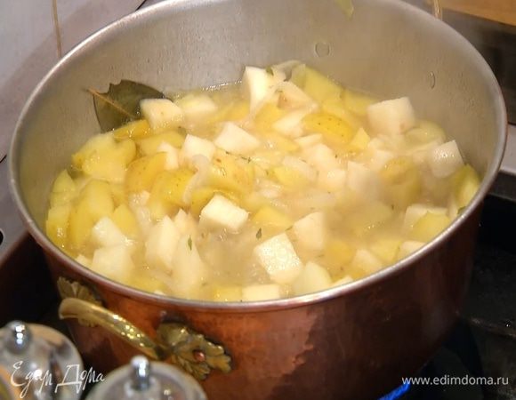 Когда лук станет мягким, добавить в кастрюлю яблоко, залить все горячим бульоном так, чтобы овощи были покрыты, снова накрыть крышкой и варить еще минут 10‒12, до готовности сельдерея и картофеля (если нужно, подлить еще бульона).