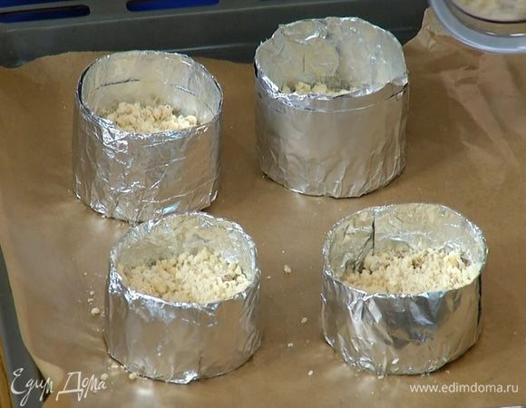 Противень выстелить бумагой для выпечки, поместить на бумагу кондитерские кольца, выложить в каждое кольцо слой яблок в соусе, затем по 1/2 ч. ложки имбирного варенья и по 2 ст. ложки с горкой мучной крошки.