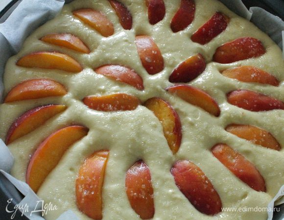 Форму для выпечки выстелить пергаментом (у меня антипригарный и я его не смазываю), равномерно распределить тесто и затем нарезанные дольками персики. Сверху посыпать небольшим количеством сахара (примерно столовая ложка).