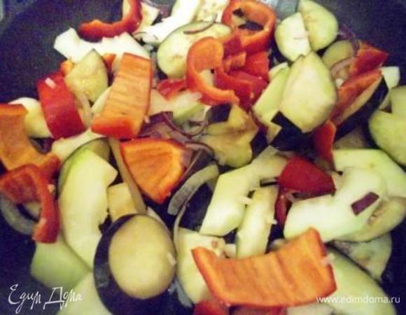 Разогреваем сковороду, наливаем масло и обжариваем сначала лук полукольцами, через пару минут добавляем измельченный чеснок, перец, цукини и баклажан порезанные крупными кусками. Тушим овощи на среднем огне минуток 10, помешиваем, если надо добавляем пару ложек воды (я добавляла 2).