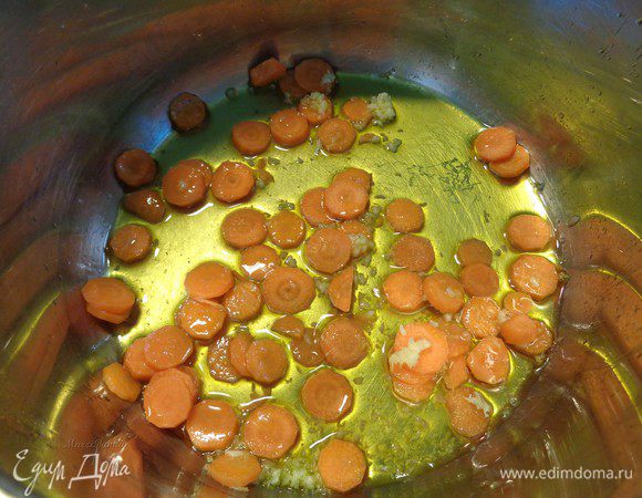 С кастрюлю, в которой будете варить суп, налить оливковое масло. В разогретое масло положить морковь и, пропущенный через пресс, чеснок.