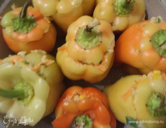 У перцев срезать крышечку, удалить семена. Нафаршировать перцы, выложить их стоя в форму для запекания, сверху накрыть срезанными крышечками, на дно налить стакан воды и запекать 30 минут при температуре 180 градусов.