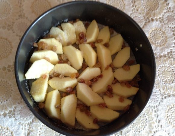 Форму проложить пергаментом и смазать сливочным маслом, разложить порезанные на четверть яблоки, изюм, присыпать ванильным сахаром. Таким образом яблоки немного карамелизируются.