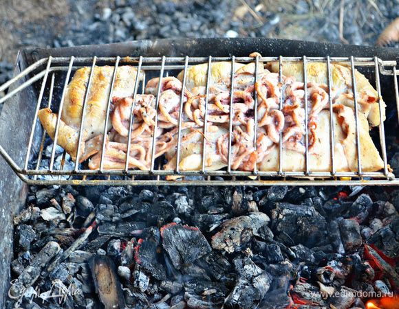 Выложить на смазанную маслом решётку гриля нафаршированные тушки кальмаров и щупальцы, ставим на горячие угли. Готовить 10 минут, переворачивая периодически решётку. 