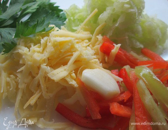 Натираем на крупной терке очищенные от кожицы огурцы и отжимаем сок. Перец режем мелкими ломтиками. Натираем сыр на крупной терке, мелко шинкуем чеснок.
Добавляем к овощам взбитые яйца, йогурт, муку смешанную с содой, зелень, растительное масло, соль, сахар и замешиваем тесто.