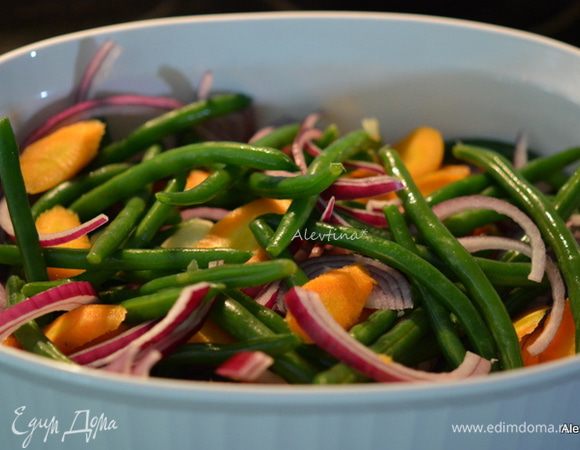 Переложить фасоль в жаропрочное блюдо или противень, смазанным маслом. Добавить очищенную и порезанную по диагонали молодую морковь, лук красный тонко нарезанный, чеснок крупный нарезанный. Посолить, посыпать черным перцем и молотым тмином.
Готовить в разогретой  духовке на 180С 45-50 мин.