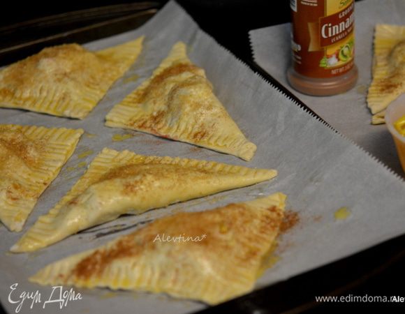Выложить на противни турноверы. Посыпать крупным сахаром с корицей. Поставить в разогретую духовку примерно на 20 минут или до золотистого цвета.