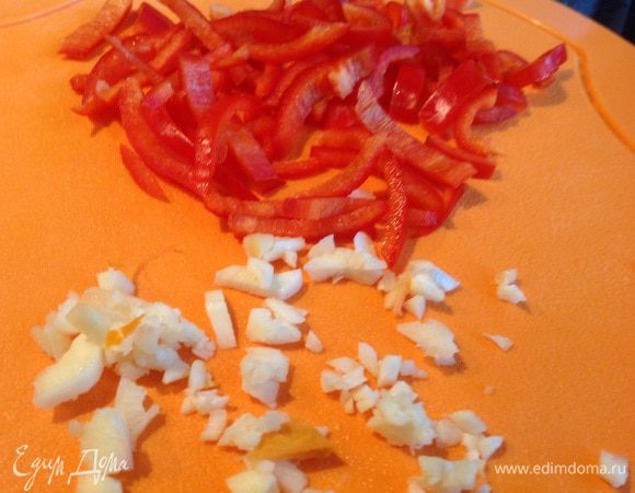 Чеснок мелко порубите, болгарский перец тоже нарежьте соломкой. Добавьте овощи к луку и обжаривайте, помешивая около 4 минут.