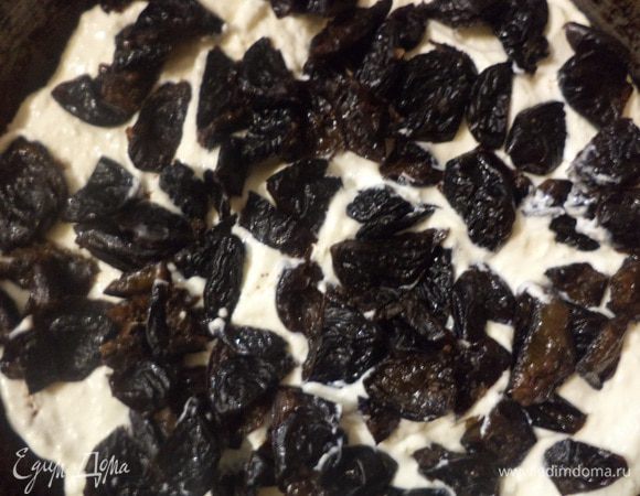 В форму, в которой выпекался бисквит, выложить один корж, нанести половину творожно-сметанной начинки, на неё выложить кусочки чернослива, затем оставшуюся половину начинки, и накрыть всё вторым бисквитным коржом.