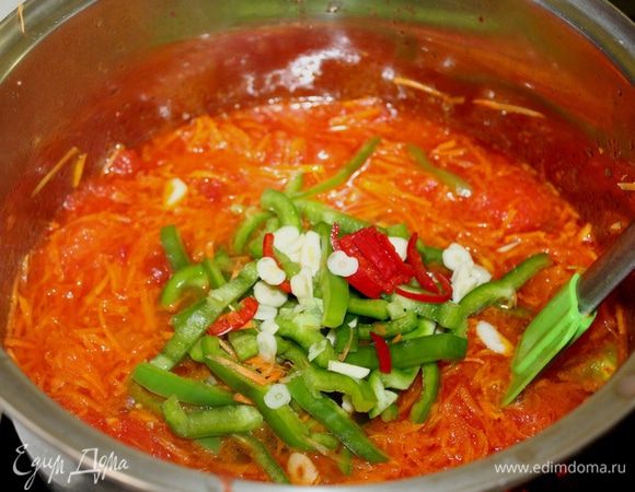 Положить нарезанные перцы, очищенный чеснок.