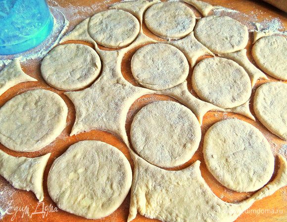 Достаём тесто и присыпаем на доску пару ложек муки, так как тесто липкое и нежное! Вырезаем кружочки шире, чем стакан, но меньше блюдца.