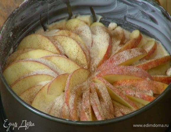 На тесто по кругу веером выложить яблочные дольки, посыпать их оставшимся сахаром и корицей.