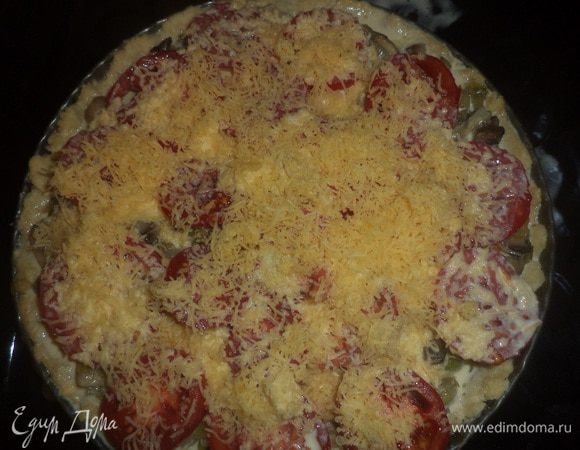 На полуиспечённый корж выложить обжаренные грибы и порей, а сверху выложить нарезанные кружочками помидоры. 
Твёрдый сыр натереть на тёрке.
Яйца взбить со сливками, добавить половину натёртого сыра, посолить, поперчить.
Залить этой смесью пирог, сверху посыпать оставшимся сыром.
Выпекать ещё 30 минут.