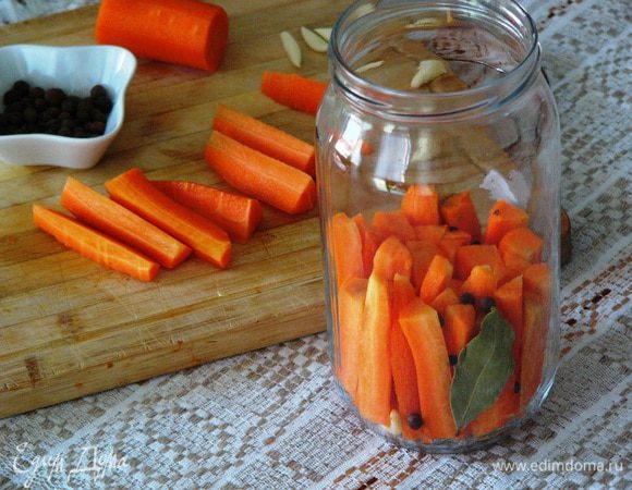 В подготовленную чистую банку начинаем плотно укладывать морковь, добавляя чеснок и специи (у меня лавровый лист, душистый перец, 2 гвоздички).