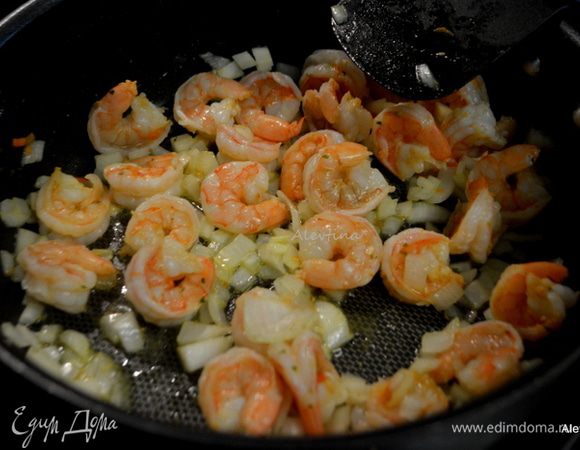 Выложить креветки на горячую сковороду с маслом. Обжаривать 3–4 минуты до розового цвета.