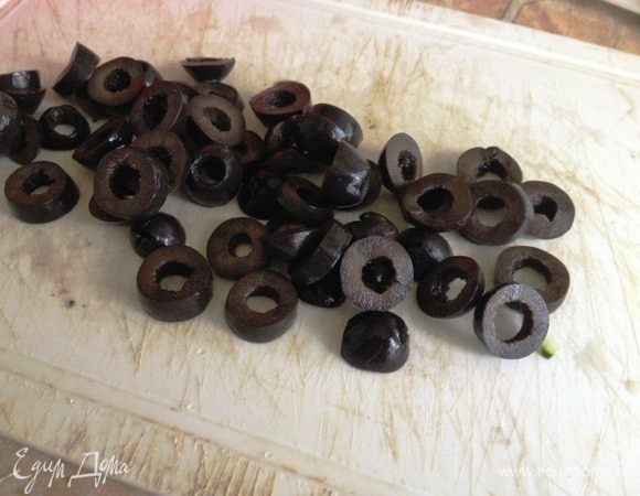 С маслин слить жидкость и нарезать колечками.