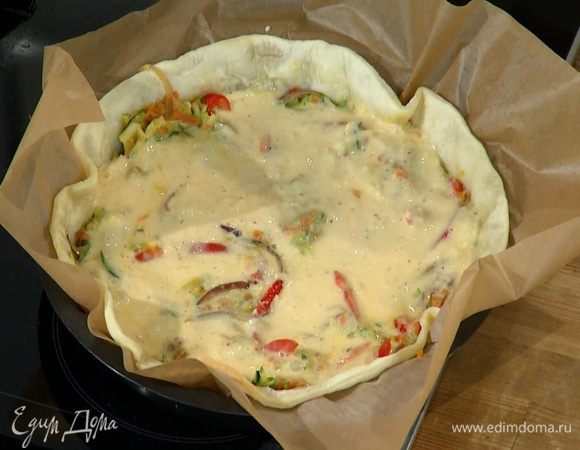 Подпеченный корж вынуть из духовки, удалить бумагу с горохом и выложить овощную начинку, а сверху равномерно распределить яично-сливочную массу.