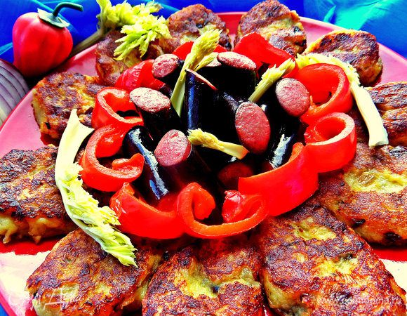 Кладём на большое блюдо золотистые оладьи. В центр высыпаем колбаски и украшаем перчиком и зеленью.