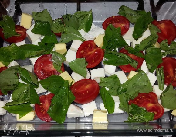 В форму для запекания равномерно выкладываем нарезанную кубиками моцареллу, сливочное масло, половинки черри и листочки базилика (рвем руками).