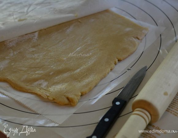 Можно поделить тесто на 2 части, мне было удобно работать с обшей массой без разделения. Выложить на бумагу для выпечки, слегка присыпать мукой, сверху второй лист бумаги и раскатать в прямоугольную форму. Так тесто не липнет к скалке и бумаге. 