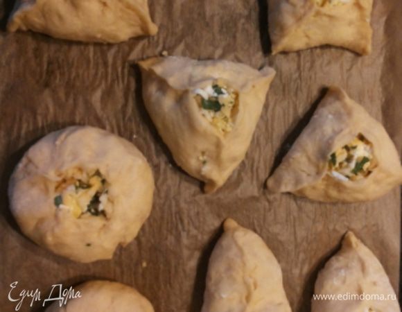 Тесто делим на 8 кусочков. Можно больше, все зависит от того, какого размера пирожки вы в итоге хотите получить (мои пирожки довольно большие). Можно сделать и одним пирогом. Каждый кусочек раскатываем в лепешечку, кладем начинку (начинки должно быть много!) и формуем пирожки кому как больше нравится: кругленькие, треугольные, квадратные или "лодочками"! Кладем на противень, застеленный пекарской бумагой, и оставляем на 20 минут. Смазываем взбитым яйцом и выпекаем в духовке при температуре 200 градусов до румяной корочки, примерно 15 минут.