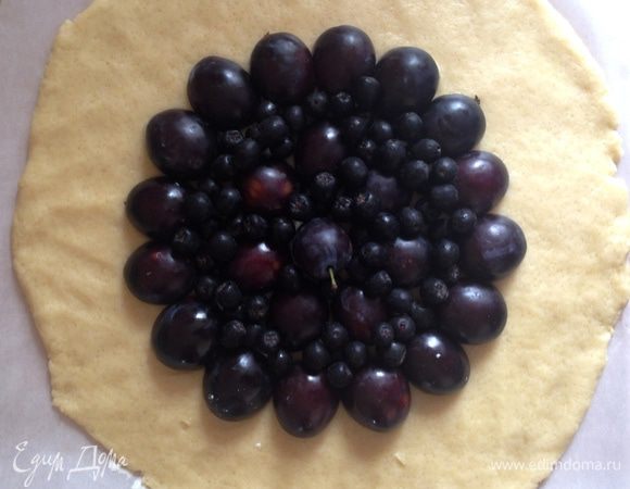 Тесто выложить на лист пергамента и раскатать в лепешку 30–33 см. Сверху выложить половинки слив и ягоды рябины.