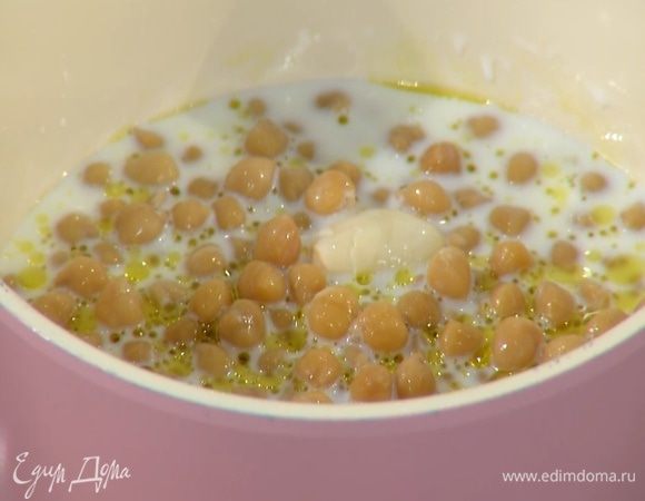 В глубокую кастрюлю влить молоко, 1 ст. ложку оливкового масла Extra Virgin, добавить чеснок, отваренный нут и прогревать, пока молоко не закипит.