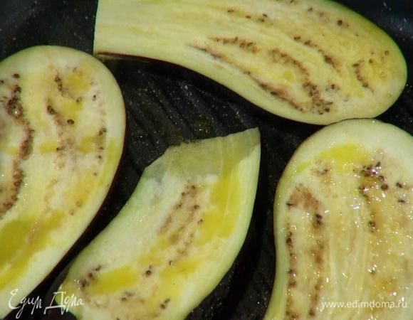 Сковороду-гриль, где жарились грибы, смазать оливковым маслом, выложить пластинки баклажана, сбрызнуть их сверху оливковым маслом и распределить масло кисточкой.