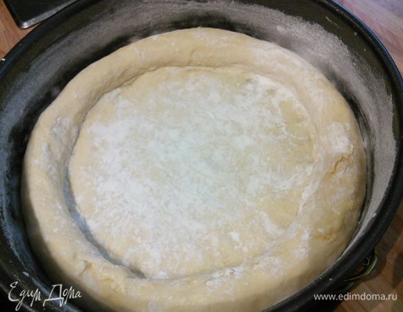 Круглую, плоскую форму диаметром около 30 см смазать маслом и посыпать мукой. Подошедшее тесто распределять пальцами (припылив чуть мукой, т. к. тесто получается очень нежное и липнет к рукам)  по форме до тех пор, пока образуется толстенький рант, а пласт теста на дне формы будет достаточно тонким. 30 мин выдержать под плёнкой в тёплом месте для отдыха. 