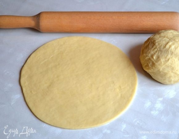 На разделочную поверхность насыпать 1/3 часть стакана сахара. Разровнять рукой. Сверху положить 1/3 часть теста, раскатать в круг.