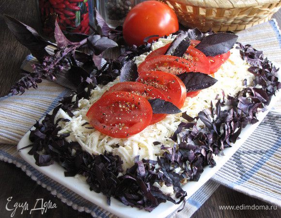 Помидор нарезать тонкими кружками и выложить на сыр. Украсить листиками базилика. Закуске дать настояться пару часов в холодильнике и можно подавать.