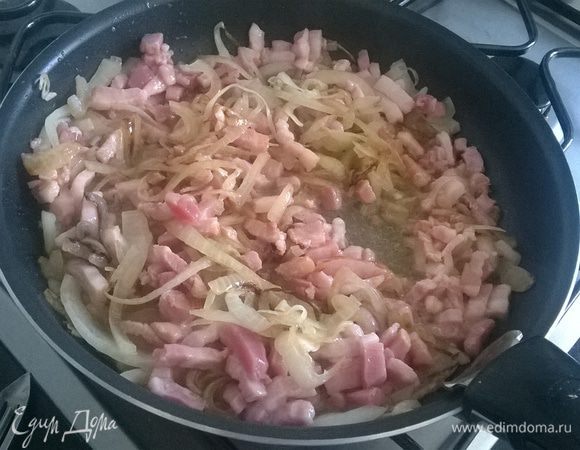 Лук режем полукольцами и обжариваем до прозрачности, добавляем бекон, порезанный кубиками или пластинками. Обжариваем пока бекон слегка не подрумянится. 