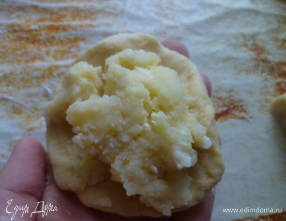 Тесто делим на 2 части, каждую часть раскатываем в колбаску и нарезаем порционно на кусочки.
Каждый кусочек расплющиваем в лепешку, выкладываем по 1-1,5 столовой ложки с горкой начинки.