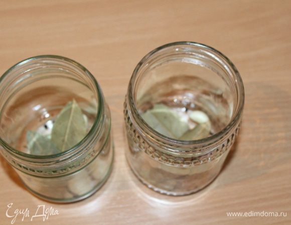 На дно стерилизованных баночек кладем чеснок и лавровый лист.