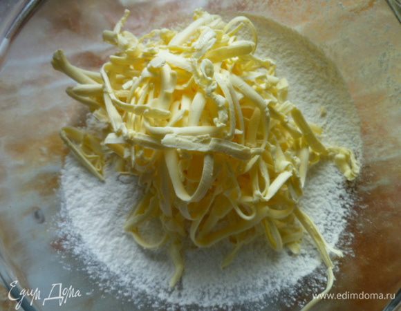 Приготовим тесто.
На дно миски насыпать немного муки, сверху натереть на крупной терке маргарин, затем сверху просеять муку (1200 мл стакан) смешанную с содой (на кончике ножа).
Руками перетереть в крошку.
Добавить соль, перемешать.