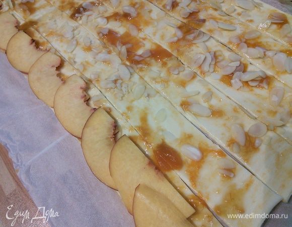 Форму от маффинов выложить бумажными формочками. Пластинки нектарина выложить слегка внахлёст кожицей чуть выступая за предел полоски теста. Скрутить в плотный рулет. 