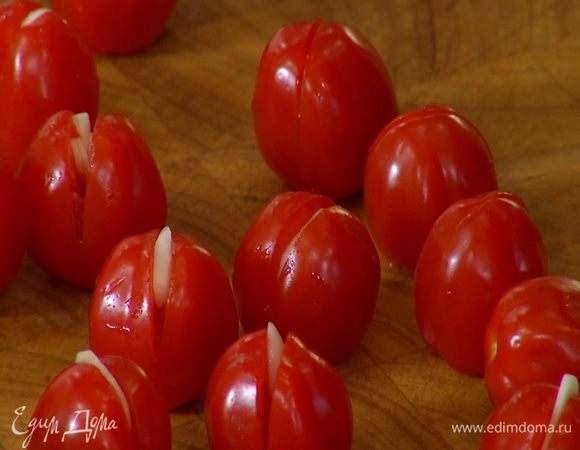 Чеснок почистить, нарезать тонкими ломтиками и вставить в разрезы помидоров.