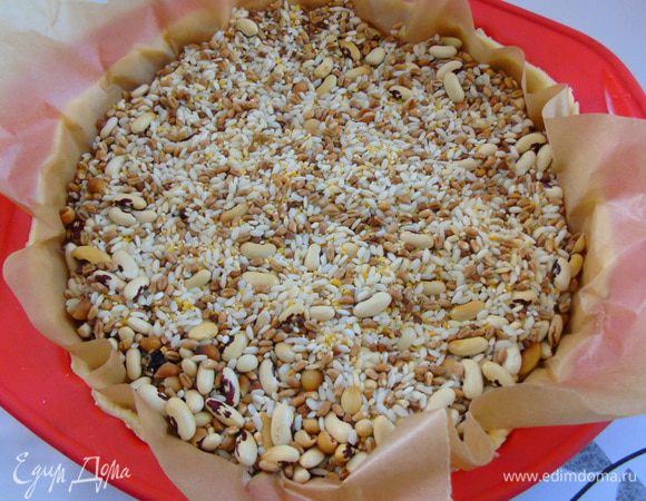 Выложить в форму и сформировать бортик. Накрыть пергаментом и насыпать сверху груз (фасоль,горох и т.д.) Отправить в разогретую до 180С духовку на 10-12 минут.